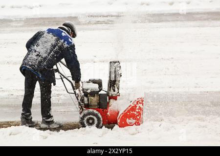 Der Arbeiter entfernt Schnee mit dem Handschneegebläse Stockfoto