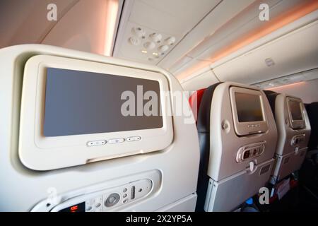 Bildschirme für Passagiere auf weichen Sitzen in modernen Flugzeugen. Stockfoto