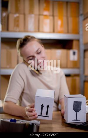 Frau, die ein Mobiltelefon oder Tablet verwendet, um mit Kunden zu kommunizieren. Lieferung von Waren über private Kurierdienste. Konzepte des Online-Verkaufs und weiter Stockfoto