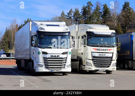 Zwei weiße schwere DAF XF-Lkw, Fahrzeug der Generation 2021 links und vorheriges Euro 6-Modell rechts geparkt am Lkw-Stopp. Salo, Finnland. April 2024. Stockfoto