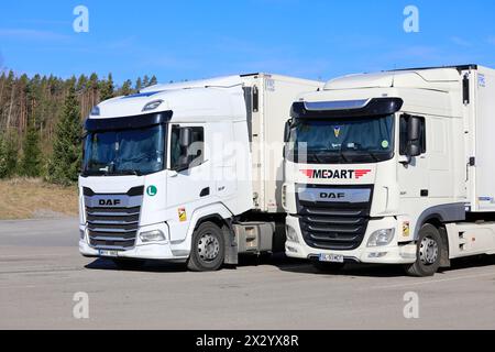 Zwei weiße schwere DAF XF-Lkw, Fahrzeug der Generation 2021 links und vorheriges Euro 6-Modell rechts geparkt am Lkw-Stopp. Salo, Finnland. April 2024. Stockfoto