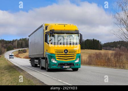 Der gelb-grüne Mercedes-Benz Actros 1845 zieht an einem Frühlingstag einen Auflieger entlang der Autobahn. Salo, Finnland. April 2024. Stockfoto