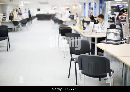 Viele Menschen arbeiten an Computern in großen Büros für Autohändler. Geringe Schärfentiefe. Konzentrieren Sie sich auf den nächsten Stuhl. Stockfoto