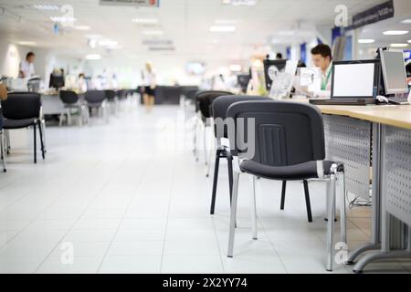 Männer und Frauen arbeiten an Computern in Autohäusern. Geringe Schärfentiefe. Konzentrieren Sie sich auf den nächsten Stuhl. Stockfoto