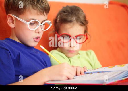 Mädchen und Junge machen Hausaufgaben, konzentrieren Sie sich auf die Scharnierbrille. Stockfoto