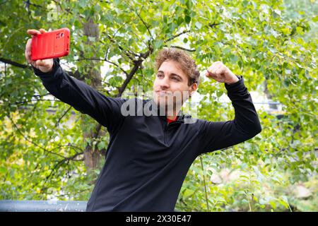 Junger Mann, der draußen ein Selfie auf einem Smartphone macht. Stockfoto