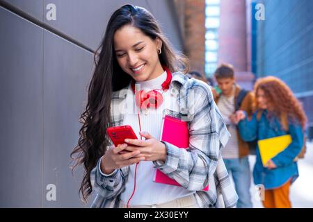Glückliche junge lateinfrau, die im Internet mit einem mobilen Gerät im Freien surft. Stockfoto