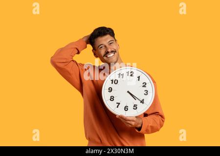 Mann hält die Uhr vor seinem Gesicht Stockfoto