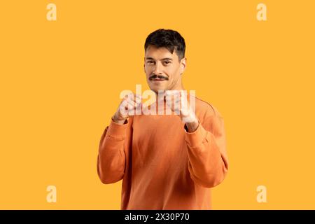 Ein junger Mann in einem orangefarbenen Sweatshirt, bereit zum Kampf Stockfoto