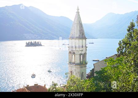 Der Glockenturm der Kirche unserer Lieben Frau vom Rosenkranz vor dem Hintergrund des Meeres, der Berge und der Perastinseln in Montenegro Stockfoto