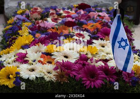 Eine Flagge des Staates Israel ruht auf einem Grab eines gefallenen Soldaten, bedeckt mit bunten Blumen auf dem Har Herzl Militärfriedhof in Jerusalem auf mir Stockfoto