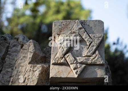 Ein ineinander greifender, sechsseitiger jüdischer Stern oder Magen David, der in einen Gedenkstein auf dem Militärfriedhof Mount Herzl in Jerusalem, Israel, gemeißelt wurde. Stockfoto