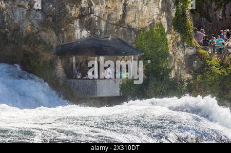 In einer Kanzel, welche auf dem Gebiet des Kanton Zürich liegt, beobachten Touristen den Rheinfall aus unmittelbarer Nähe. (Neuhausen am Rheinfall, SC Stockfoto