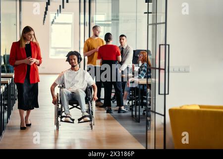 Eine vielfältige Gruppe junger Berufstätiger, darunter Geschäftsfrauen und ein afroamerikanischer Unternehmer im Rollstuhl, arbeiten zusammen Stockfoto