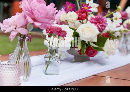 Tisch mit Kerzen und strukturierten rosa und weißen Blumen. Inspiration für Veranstaltungen, Gartenparty. Stockfoto