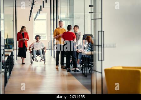 Eine vielfältige Gruppe junger Berufstätiger, darunter Geschäftsfrauen und ein afroamerikanischer Unternehmer im Rollstuhl, arbeiten zusammen Stockfoto