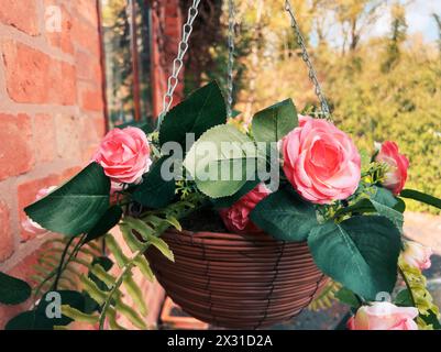 Hängender Korb voller Plastikblumen Stockfoto