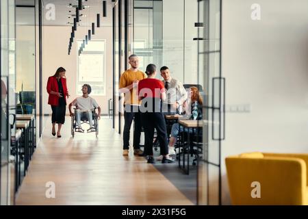 Eine vielfältige Gruppe junger Berufstätiger, darunter Geschäftsfrauen und ein afroamerikanischer Unternehmer im Rollstuhl, arbeiten zusammen Stockfoto