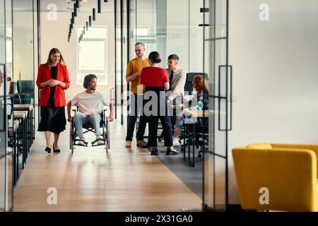 Eine vielfältige Gruppe junger Berufstätiger, darunter Geschäftsfrauen und ein afroamerikanischer Unternehmer im Rollstuhl, arbeiten zusammen Stockfoto
