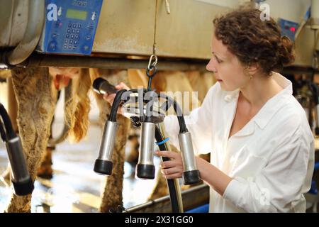 Junge Frau in weißen Mänteln bereitet Maschine für das Melken von Kühen auf dem Bauernhof vor. Stockfoto