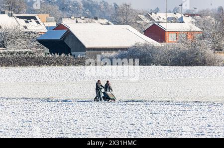 Einige Menschen geniessen mit einem Kinderwagen einen Spaziergang in der winterlichen Landschaft. (Rafz, Schweiz, 11.12.2022) Stockfoto