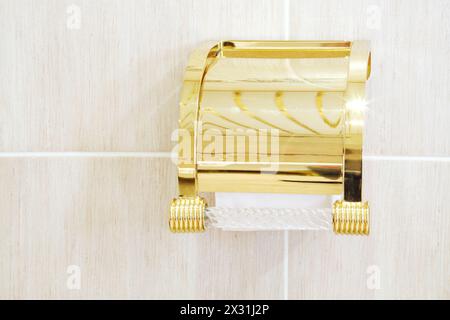 Vergoldeter Halter mit Rolle weiches weißes Toilettenpapier im Badezimmer. Stockfoto