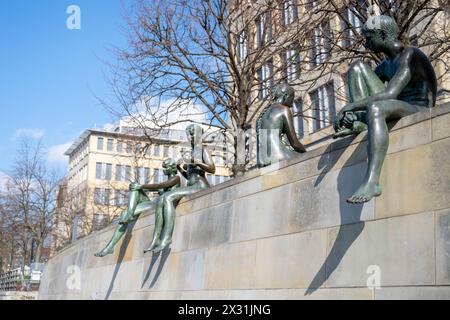 Drei Mädchen und ein Junge Skulpturen auf einer Steinmauer am Spree Riverbank in Berlin. Stockfoto