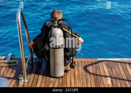 Ein Teenager in einem Taucheranzug mit einem Sauerstofftank auf dem Rücken Stockfoto