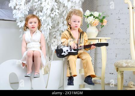 Ein kleines Mädchen in weißem Kleid und Popmusiker mit Gitarre sitzen auf Briefen Love Stockfoto