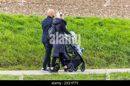 Ein Mann und eine Frau spazieren mit ihrem Kind im Kinderwagen auf einem Fussgängerweg. (Oberglatt, Schweiz, 02.10.2022) Stockfoto