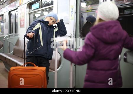 Junge und Mädchen in einer Jacke mit Koffern in einem leeren U-Bahn-Auto Stockfoto