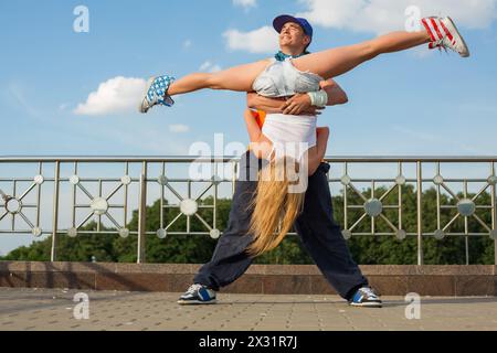 Junge Leute tanzen modernen Tanz auf der Straße, Mädchen, die kopfüber gespalten sind. Stockfoto