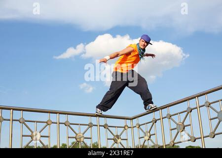 Ein Mann steht während des Breakdance auf einem dünnen Zaun Stockfoto