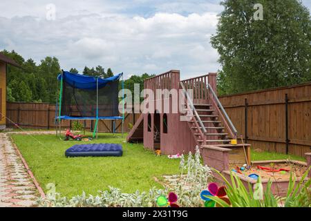 Kinderrutsche, Trampolin und Sandkasten auf dem Spielplatz im Landhaus Stockfoto