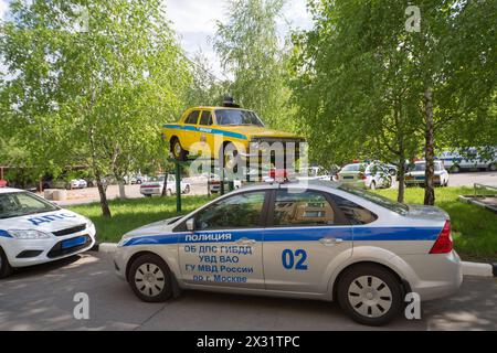 MOSKAU - 14. April 2013: In Moskau, Russland, befinden sich neue Polizeiautos neben dem Sockel mit einem alten Milizwagen auf der Straße. Stockfoto