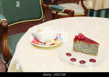 Eine Tasse Cappuccino-Kaffee und ein Stück Kuchen auf dem Tisch mit Tischdecke. Stockfoto