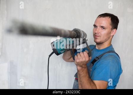 Der Arbeiter macht ein Loch mit einem Perforator Stockfoto