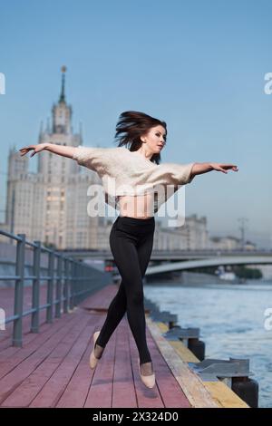 Die junge schöne Frau tanzt abends Ballett am Wasser Stockfoto