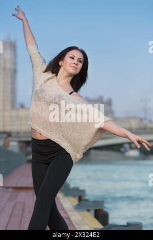 Eine junge Frau steht in Ballettposition am Wasser Stockfoto