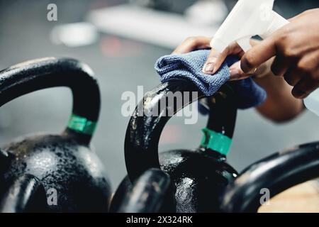 Gym, Reinigung oder Hand mit Desinfektionsmittel für Kettlebell, Sicherheit oder Vorbeugung oder Keime, Viren und Bakterien. Gewichte, Spray oder Sportclub-Hausmeister mit Stockfoto