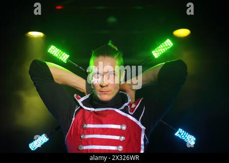 Aufführung eines Mannes mit Tätowierung und schrecklichen Schülern in Samurai-Garderobe mit Glühstäben, hinter seinem Rücken gekreuzte Stöcken. Stockfoto