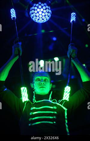 Mann mit schrecklichen Schülern in Samurai-Gewänder mit Glühstäben auf der Bühne mit Lichtkugel Stockfoto