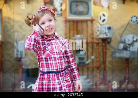 Kleines Mädchen in rosa spricht mit dem Handy und steht in der Nähe der Schaufenster im Einkaufszentrum. Stockfoto