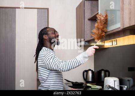 Afroamerikaner Junge benutzen Staubreinigung in der Küche zu Hause Stockfoto