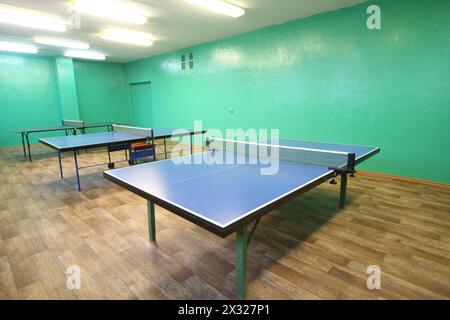 Drei blaue Tischtennisplatten im Zimmer mit grünen Wänden Stockfoto