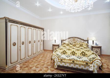 Luxuriöses Schlafzimmer mit vergoldetem Doppelbett und Kleiderschrank im klassischen Stil. Stockfoto