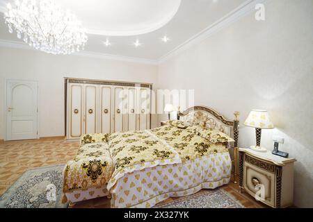 Luxuriöses Schlafzimmer mit vergoldetem Doppelbett und Nachttischen im klassischen Stil. Stockfoto