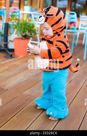 Kleiner Junge im Tigerkostüm in einem Café mit Kreide in der Hand Stockfoto