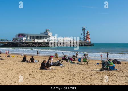 West Cliff Beach, Bournemouth, Großbritannien - 30. März 2024: Menschen, die sich am Strand entspannen, mit Bournemouth Pier im Hintergrund. Stockfoto