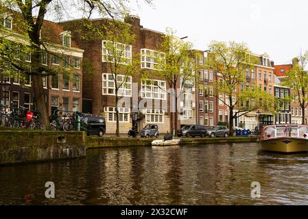 Blick auf die Vororte von Amsterdam von einem holländischen Kanal Kreuzfahrtschiff mit einem Boot voller Touristen Niederlande EU in der alten Gegend von Amsterdam Stockfoto